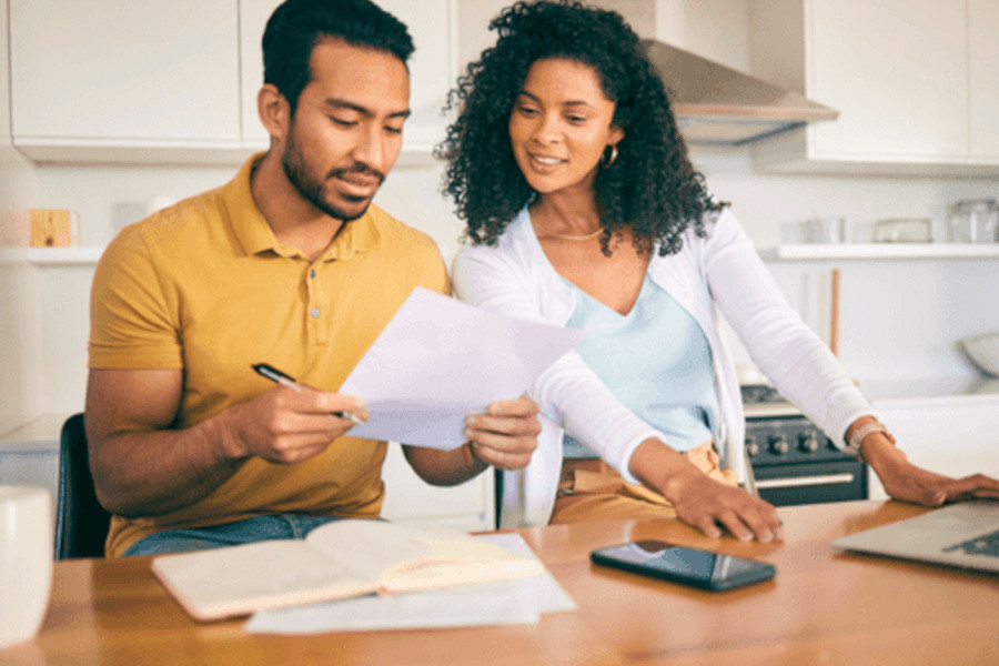 Homebuyers reviewing mortgage paperwork at a kitchen table
