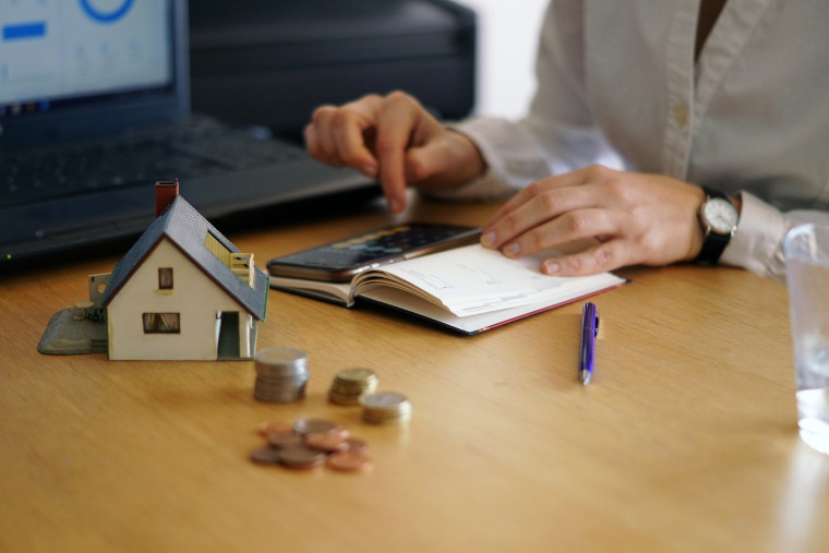 Desk with a miniature house, coins, and paperwork